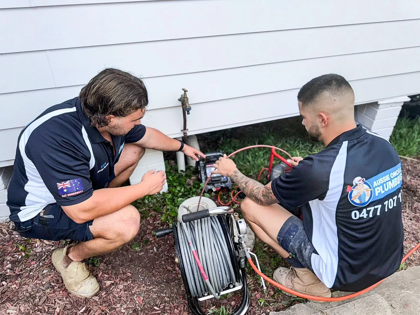Two plumbers running a drain camera at the outside sewer point